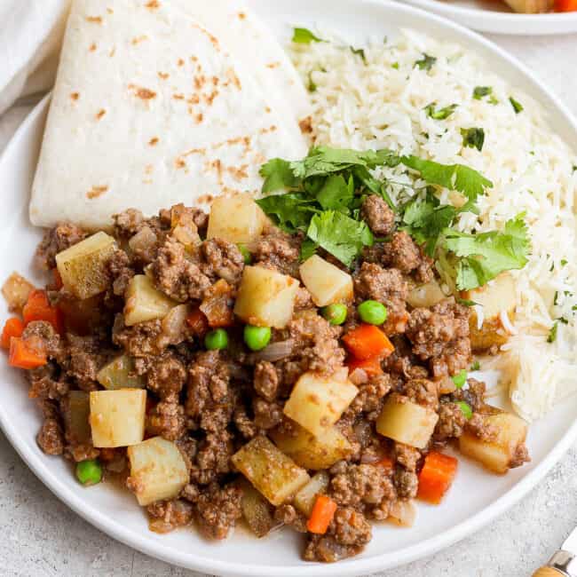 Mexican picadillo on a plate with rice and flour tortillas.